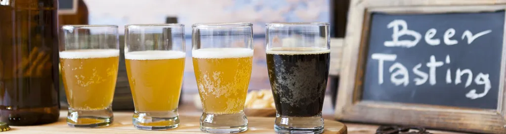 Four different beers lined up next to a sign that says "Beer Tasting"